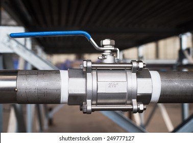 Stainless steel, 2.5 inch ball valve at an industrial workshop. Shallow depth of field with the valve in focus.