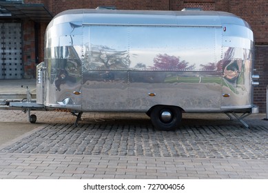 Stainless steel airstream caravan with reflection outside the Royal Shakespeare Theatre in the UK