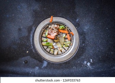 A Stainless Steel Basket Strainer And Drain In The Kitchen Sink With Leftover Food Scraps That Clog Up The Drain And Block The Flow Of Water. 