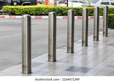 stainless steel bollards on footpath walkway near car park lot.