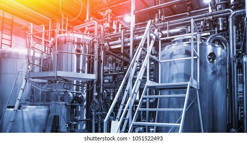 Stainless steel brewing equipment : large reservoirs or tanks and pipes in modern beer factory. Brewery production concept, industrial background in blue color and red light, toned - Powered by Shutterstock