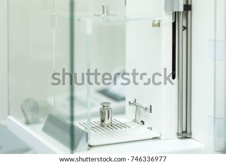 Stainless steel calibration weight placed on the analytical balance pan for  the calibration test, concept of quality control laboratory in pharmaceutical industry.