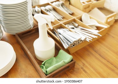 Stainless Steel Cutlery Spoon, Forks, Knives And Dished Well Organized On A Self Service Station In A Cafe Or Restaurant With 70% Alcohol Spray To Clean The Table. Covid 19 Pandemic New Normal. 