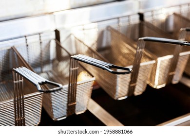 Stainless steel deep fryer wire baskets hanging on shelf. - Shutterstock ID 1958881066