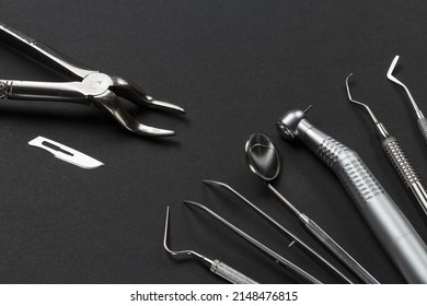 Stainless steel dental pliers and a blade. Plugger, tweezers, a mouth mirror, a dental handpiece with bur, a curette and a dental restoration instrument on the black background. Medical tools.