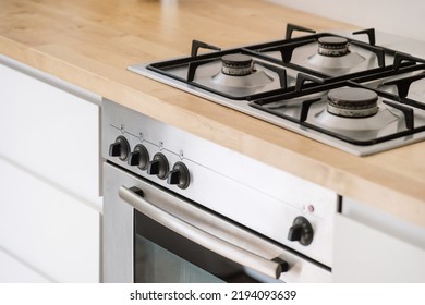 stainless steel gas cooker built in wooden countertop and electric oven with control panel at contemporary kitchen