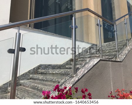 stainless steel Glass or glazed hand rail at entrance stair case steps with the planter box flowers which giving elegant look reception area of an  commercial building