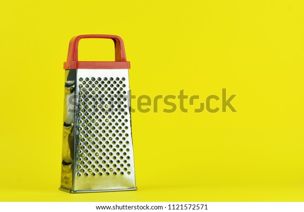 Stainless\
steel grater isolated. Kitchen accessories. Tools for cooking.\
Isolated on yellow background. For your\
design.