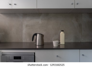 Stainless Steel Kettle With White Cup And Milk Bottle On Dark Grey Kitchen Bench (selective Focus)