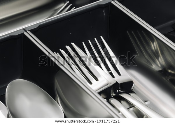 Stainless steel\
Kitchen utensil cutlery drawer organizer tray with simple set of\
tools, spoons and forks. Close\
up.