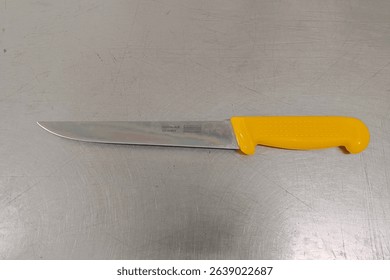 A stainless steel knife rests on a smooth stainless steel table. Its sleek blade reflects the polished surface beneath. - Powered by Shutterstock - Get 15% off with code: PIKWIZARD15