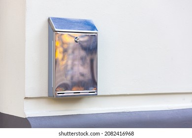 Stainless steel metal mailbox on the white wall of the house
