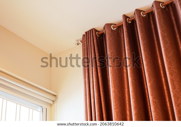 stainless steel ring top rail or grommet and\
wooden pole with luxury silk red brown Curtain on white wall beside\
the window , house interior\
concept