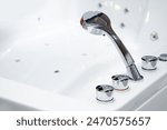 Stainless steel shower and water faucet or water tap at the edge of jacuzzi bathtub. Sanitary ware design for luxury bathroom