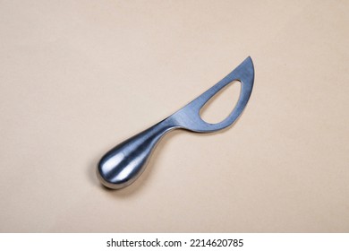 Stainless Steel silver Cheese Knife with hole in it on a beige backdrop - Powered by Shutterstock