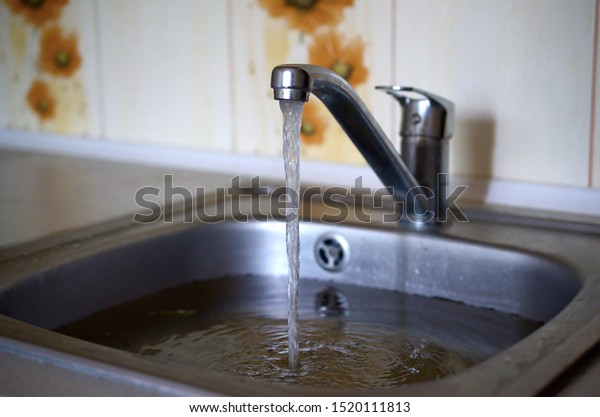 Stainless steel sink plug hole close up full of\
water and particles of\
food