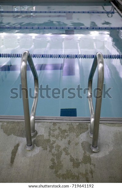Stainless\
steel steps into a swimming pool on a paving surround with wet\
splashes in a sport and recreation\
concept