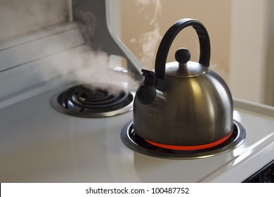 Stainless Steel Tea Kettle Coming To A Boil On A White Stove Top.