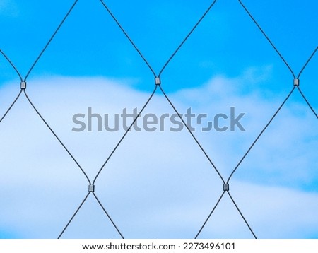 stainless steel twisted wire cable fence detail. diamond pattern shape net. clear blue sky background. modern silver color fence material. abstract frontal view. macro detail. rust free steel.