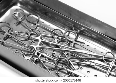 Lot of stainless surgical needle drivers lying down on steel sterilization tray for sterilize and pack medical surgery instrument. Healthcare and medicine concept. Selective focus.