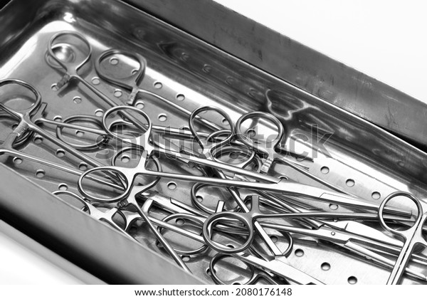 Lot of stainless surgical needle drivers lying\
down on steel sterilization tray for sterilize and pack medical\
surgery instrument. Healthcare and medicine concept. Selective\
focus.