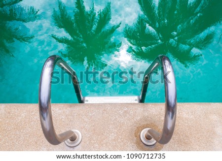 A stair at the side of swimming pool, reflection of palm tree on water for summer concept