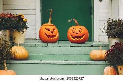 Staircase autumn decor. House entrance with halloween pumpkin decoration on wooden stairs, two jack o lanterns with spooky faces on porch of apartment building during all hallows eve - Powered by Shutterstock