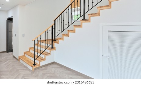 Staircase with black iron frame contrasting with hardwood colored stairwell - Shutterstock ID 2316486635
