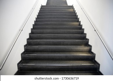 Staircase with black stone steps and steel handrails. Abstract modern architecture or interior background in concept of ascent or moving up.