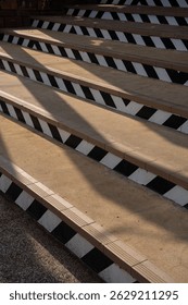 A staircase with black and white diagonal patterns, casting long shadows in sunlight, creates striking visual effect