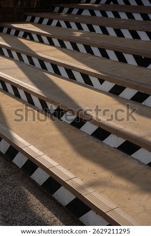 A staircase with black and white diagonal patterns, casting long shadows in sunlight, creates striking visual effect