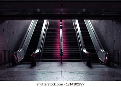 Staircase and Escalators leading down into a Subway Station with Neon Lights