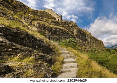 Staircase leading up to the majestic ruins of Tourbillon Castle in Sion, Switzerland. Mesmerizing view of the stone hilltop, castle walls and lush vineyards below