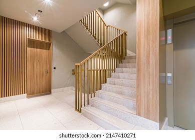 Staircase in modern block of flats. Finished with wood wall panels, tile floor. Interesting balustrade. - Shutterstock ID 2147410271