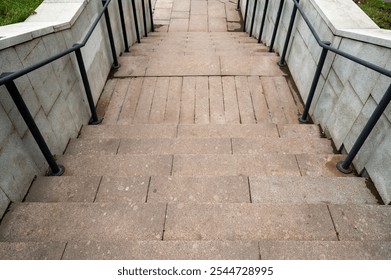 Staircase in the park with stone steps and steel railings. Hill with green grass. - Powered by Shutterstock