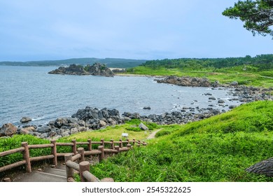 Staircase path through lush greenery leading to a rocky beach on the Tanesashi coastline, Aomori prefecture, Japan  - Powered by Shutterstock