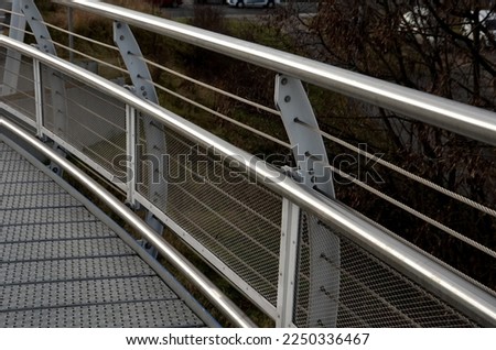 staircase and wide pedestrian bridge with perforated metal floor. galvanized sheet metal with circular holes. white railings like on a ship in the arch. handrail made of polished stainless steel pipe.
