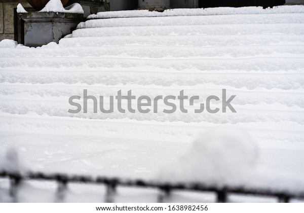 Stairs covered with snow from the first snow fall of\
the year. Winter concept, snowy staircase covered with a deep layer\
of snow