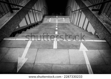 Stairs down to a subway in Hamburg, directions marked with arrows, black and white, horizontal
