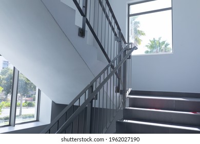 Stairs lit by daylight from windows on landing of staircase in mid 20th century building. architecture and practical interior design.