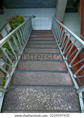 Stairs with metal handle and rough textured flooring to prevent people getting slipped down.