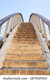 Stairs on a stonemason pedestrian bridge with handrails leading up into the sky