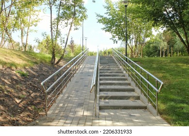 Stairs and ramp with metal railings for the passage of strollers and wheelchairs in public park. Concept of comfortable barrier-free urban environment in city. Pathway for people with disabilities - Shutterstock ID 2206331933
