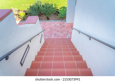 Stairs with red tile steps heading to the red stone pavement downstairs