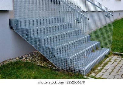 Stairs to a residential building made of stainless steel grid. galvanized stair grating made of expanded metal. lawn concrete sidewalk.  - Shutterstock ID 2252606679