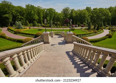 Stairs with stone railings balusters and iron lanterns on the background of the park with a luxurious landscape design walking path for walking, green lawns and a variety of bushes. - Shutterstock ID 2123234927