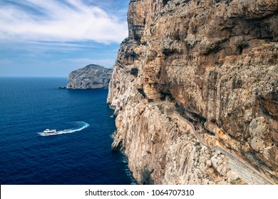 Stairway in limestone rock to stalactite Neptune cave. Boat leaving Grotte di Nettuno in Sardinia, Italy