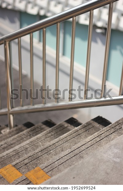 Stairway to the old, grungy stair footbridge or\
overpass with  yellow line divided into two sides for walking up\
and down, Stainless steel railing for people walk cross the road\
crossing safety.