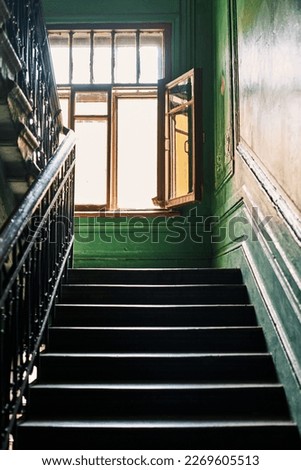 Stairways with steps in St. Petersburg paradnaya, view of open window, colored painted green walls with pattern stucco molding, forged metal railings Authentic retro interior communal homes