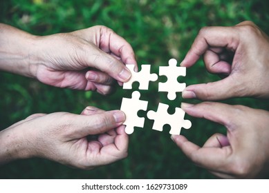 Stakeholders Business Team Holding Jigsaw Puzzle As A Team Building And Organization Connection Symbol. Teamwork And Connection Conceptual.